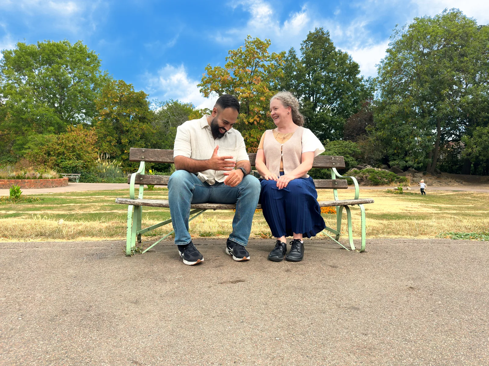 Two people laughing together on a park bench.