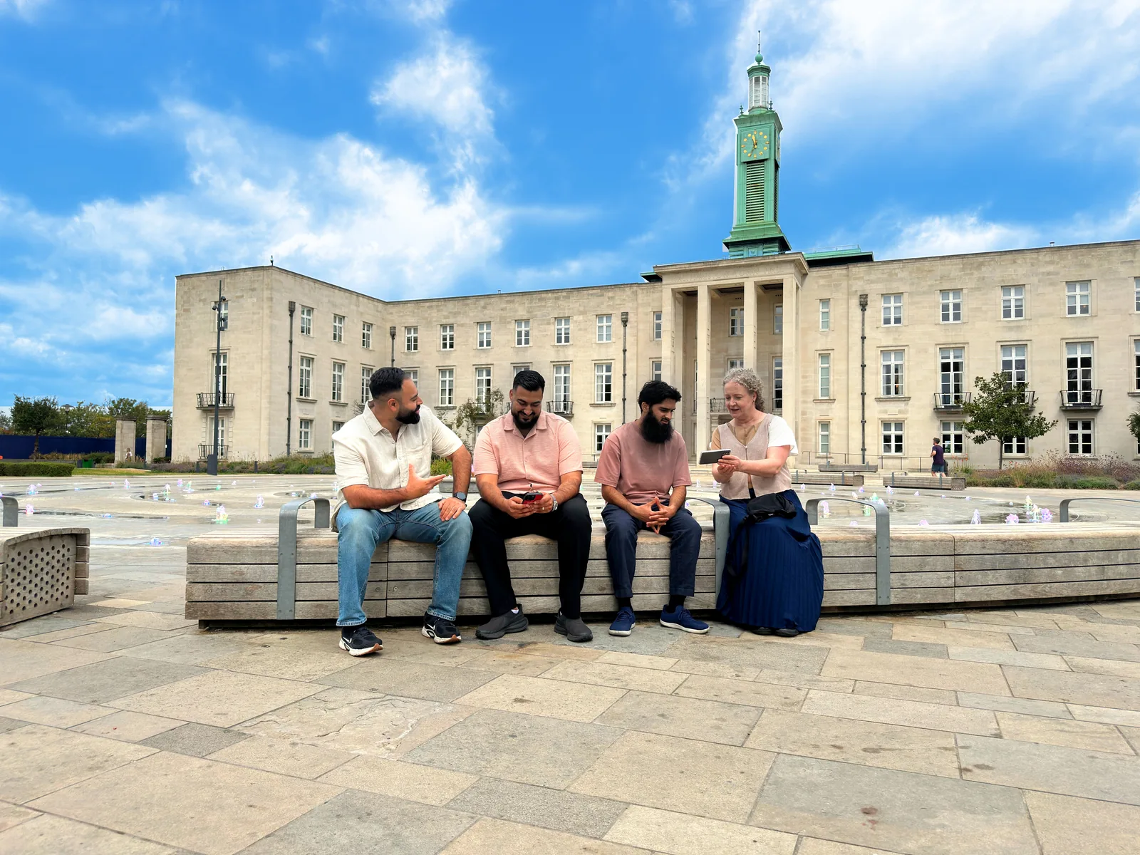 Four people sitting together outside Waltham Forest Town Hall.